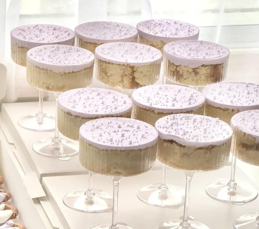 Lavender topped cake martinis in stemmed glasses, dusted with white sugar pearls.