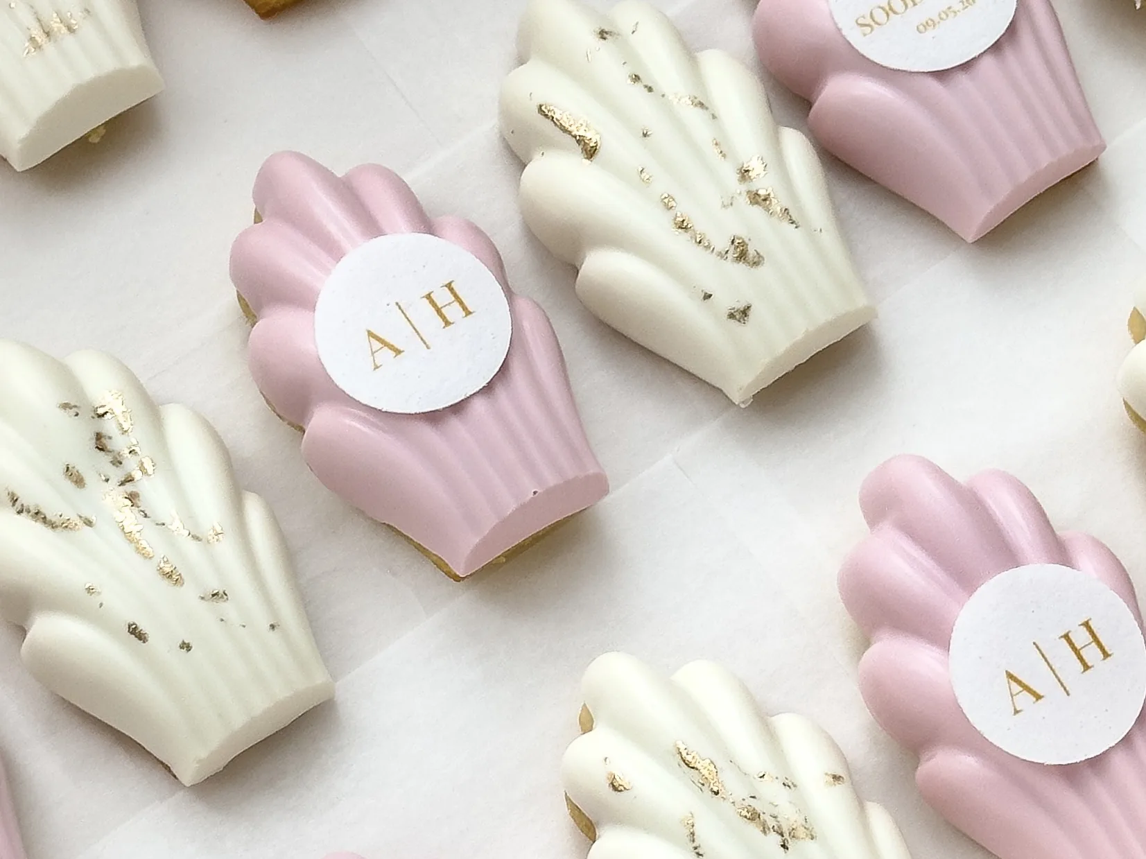 Pink and ivory chocolate covered madeleines with gold leaf and round monogram plaques.